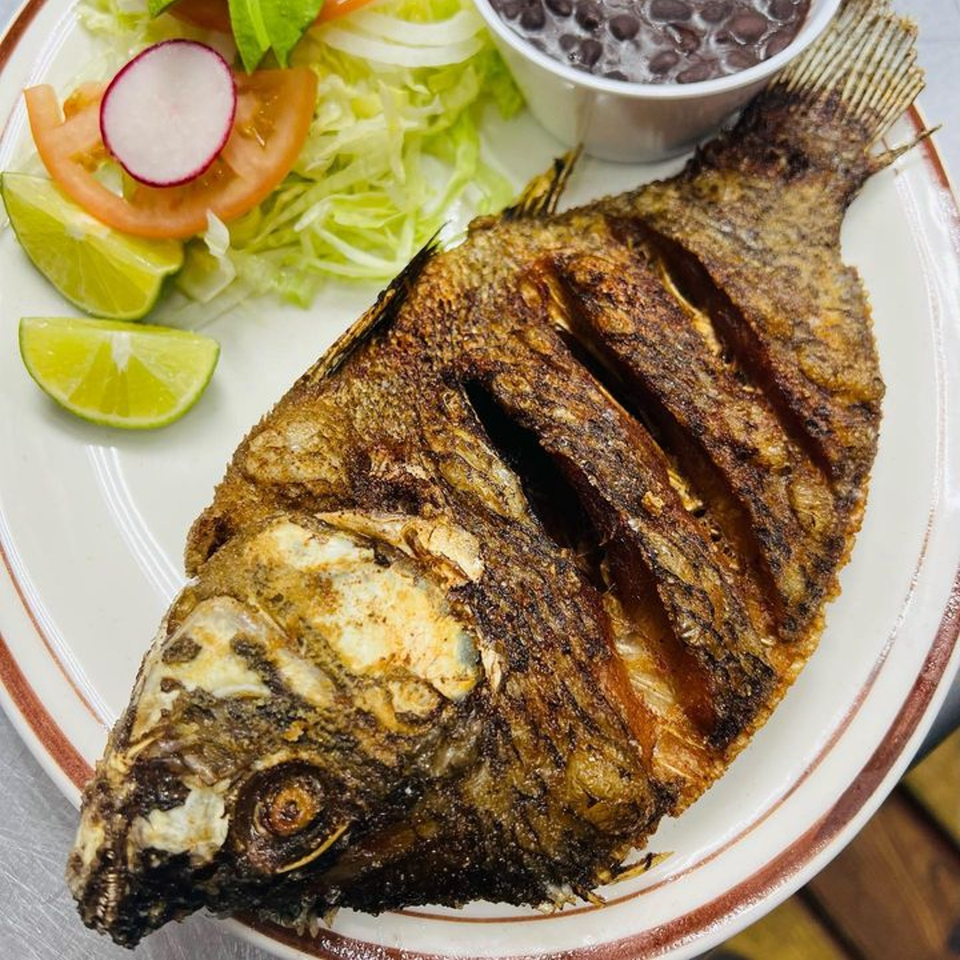 Whole fried fish with a side of black beans, salad, and lime wedges at La Fortuna.